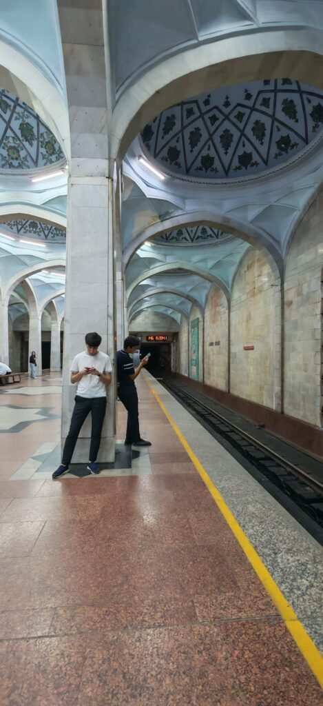 Dos personas juntas en el metro de Taskent mirando el móvil sin mirarse